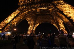 People gather at the base of the Eiffel Tower at night.jpg