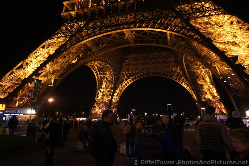 People gather at the base of the Eiffel Tower at night.jpg